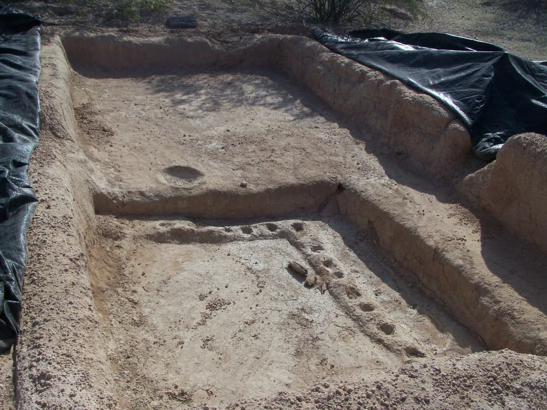 High-angle view of an excavated Hohokam earthen feature in daylight.
