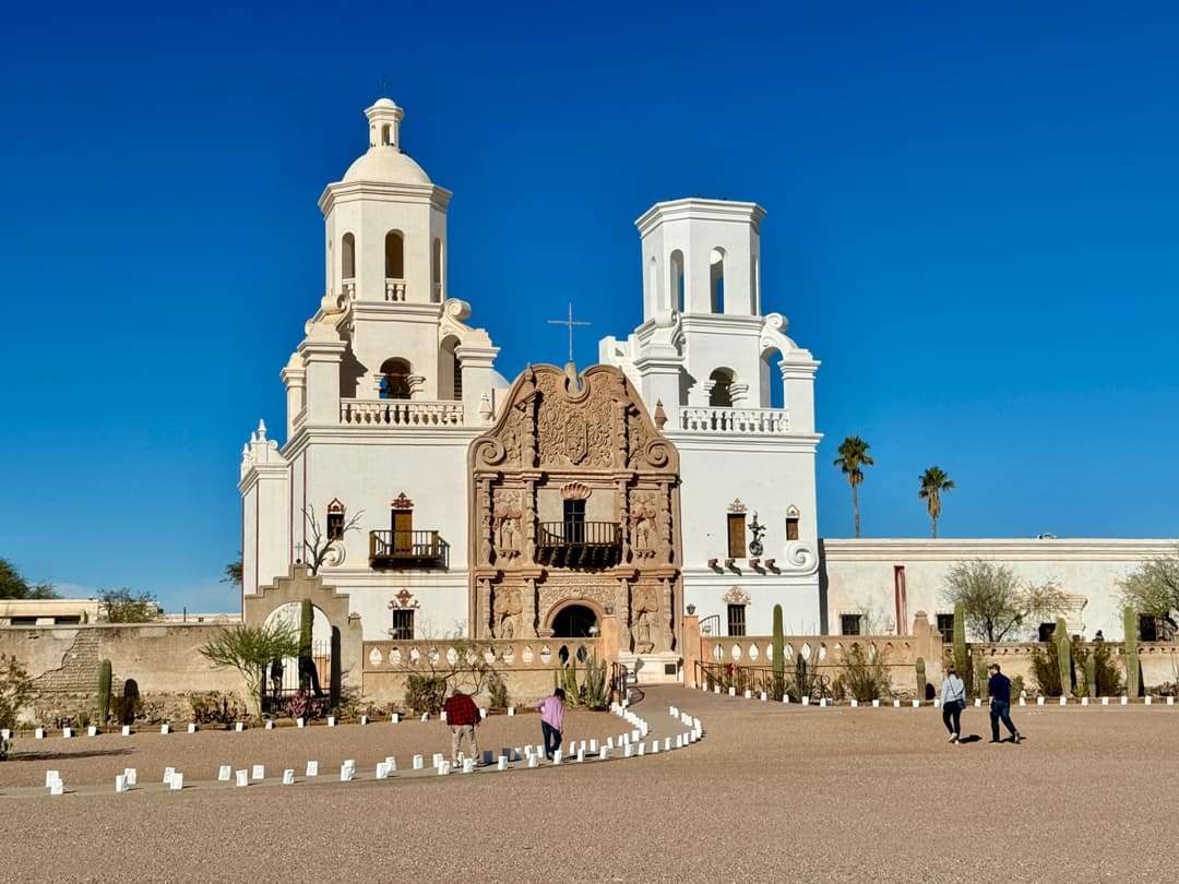 Wide-angle front elevation of Mission San Xavier del Bac in daytime.