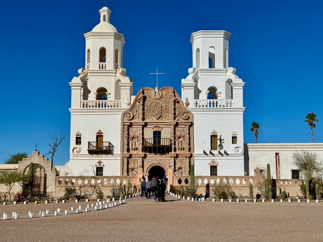 Front facade of Mission San Xavier del Bac under a clear blue sky.