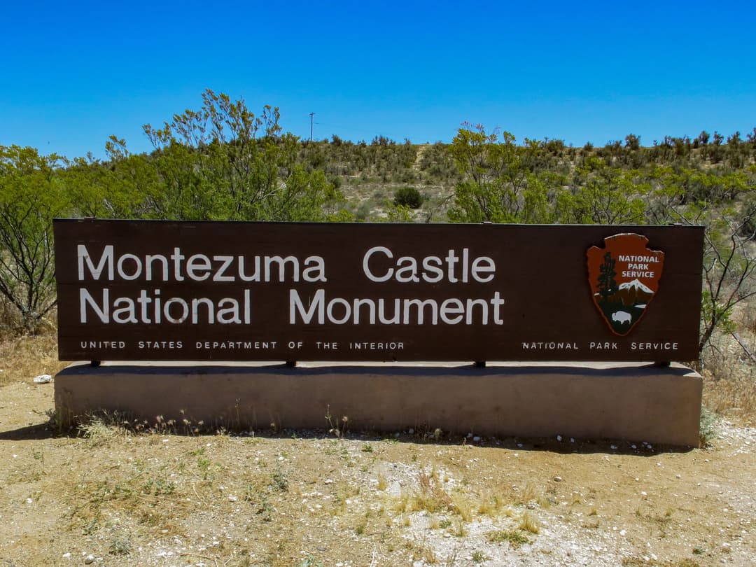 Entrance sign for Montezuma Castle National Monument in bright daylight.