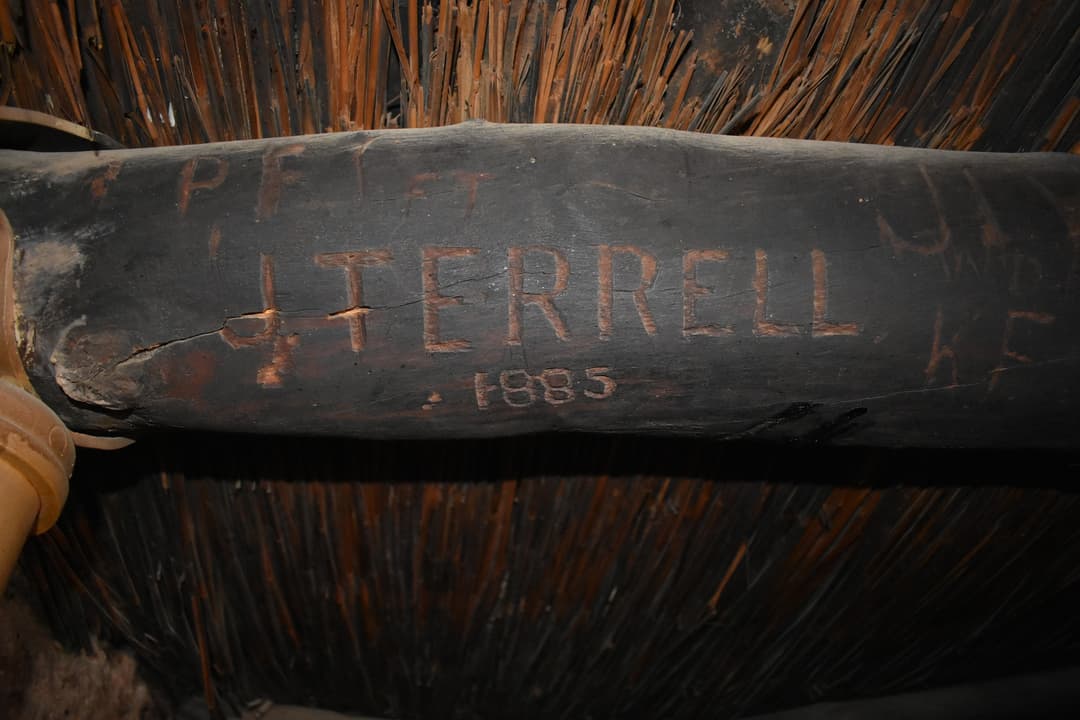 Historic 1885 inscription carved into a wooden ceiling beam.