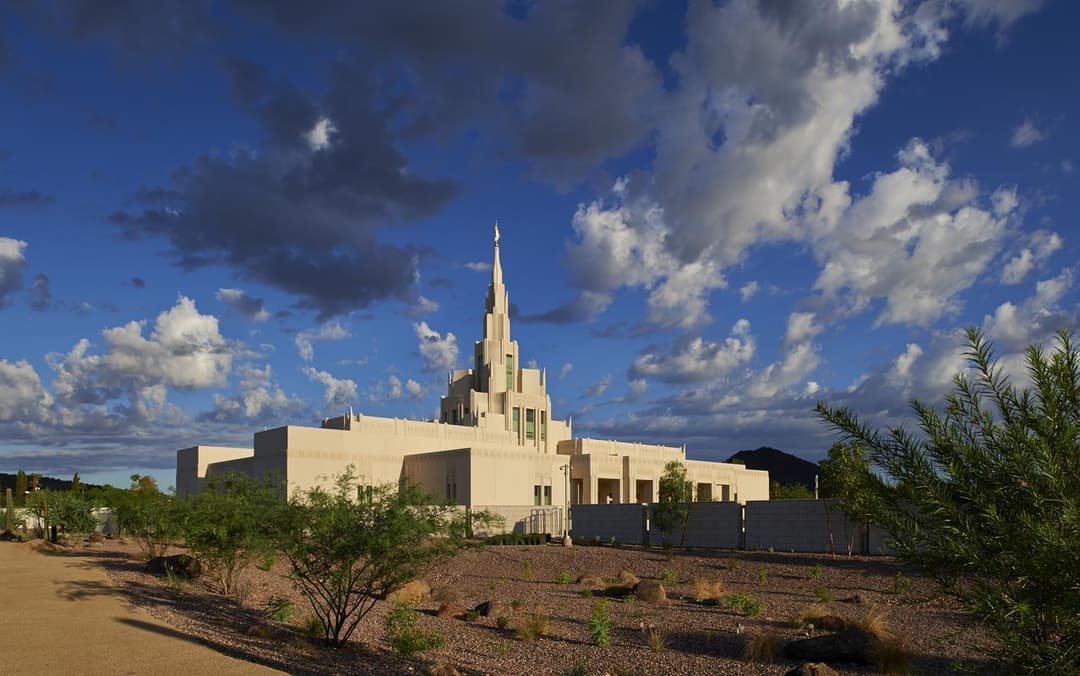 Wide exterior view of the Phoenix Arizona Temple set against a dramatic cloudy sky.