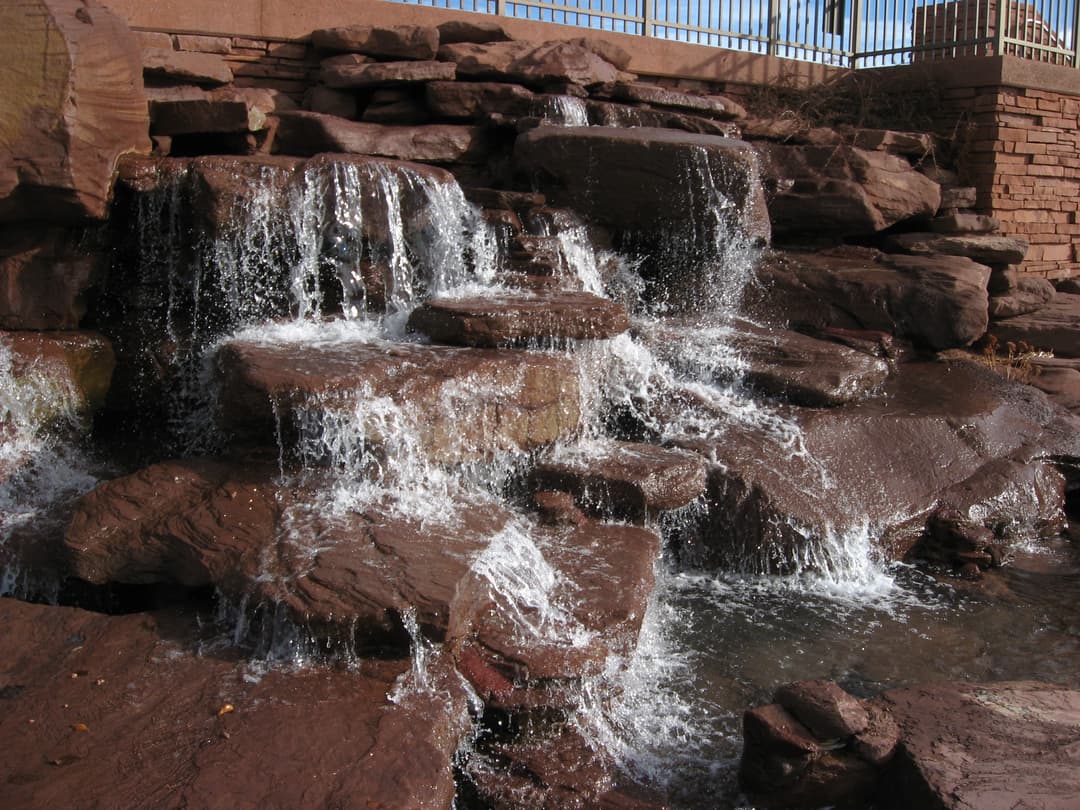 Cascading red rock waterfall feature on the temple grounds.
