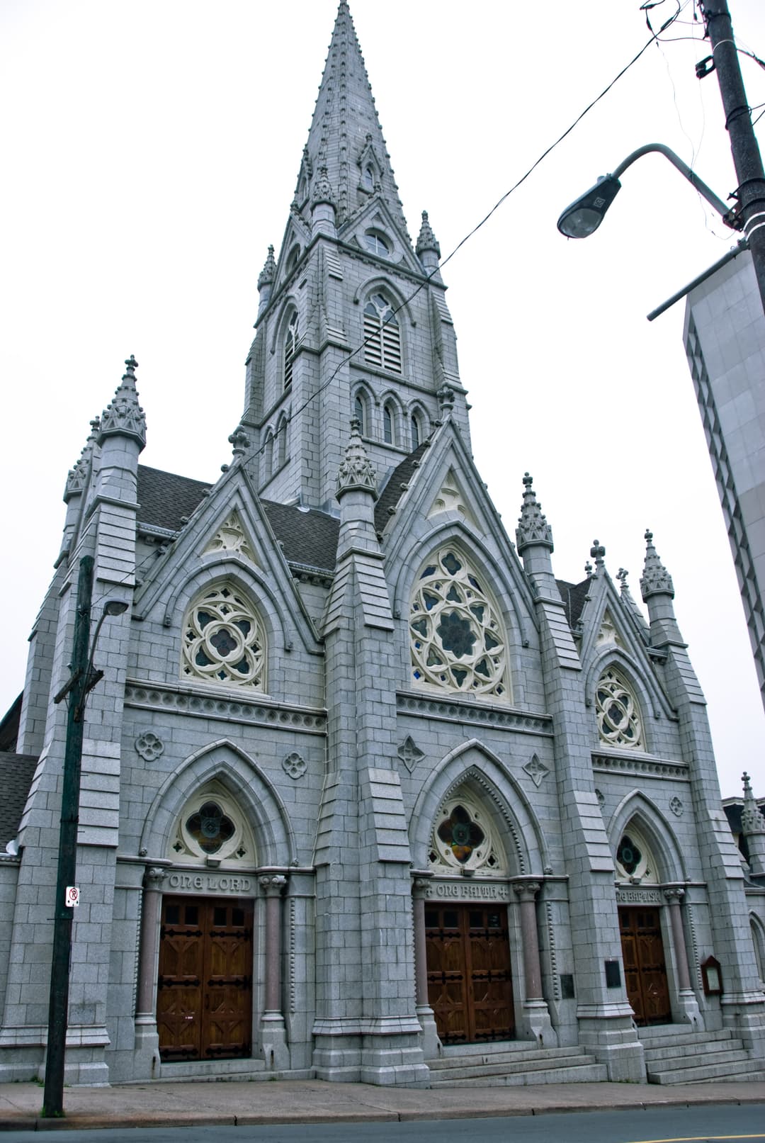 Low-angle exterior view of the granite Gothic facade and central spire.