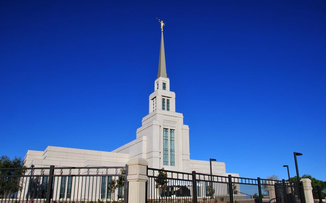 Low-angle daytime view of the Gila Valley Arizona Temple spire and fence.