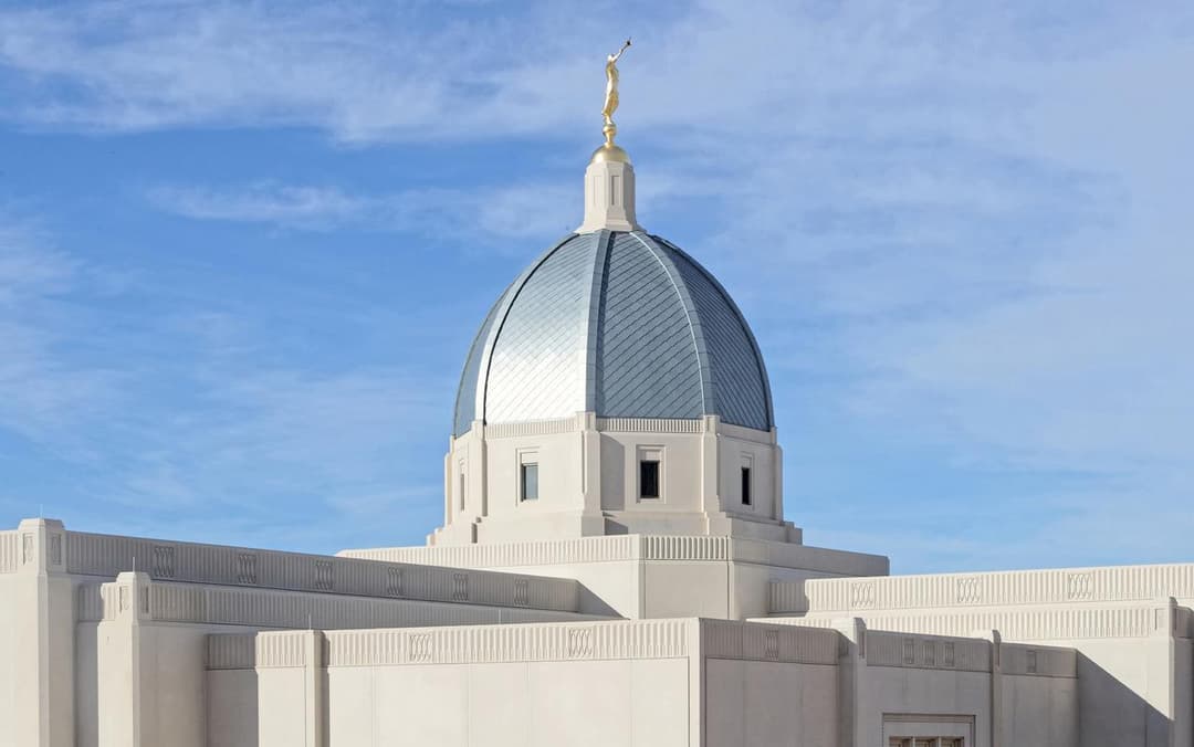 Low-angle view of the central dome and Angel Moroni statue in daytime.