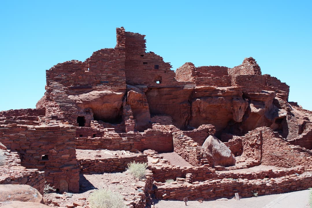 Wide-angle daylight view of multi-story sandstone ruins at Wupatki Pueblo.