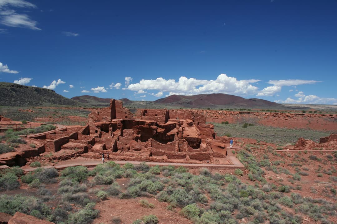 Wide elevated view of Wupatki Pueblo ruins against a volcanic landscape.