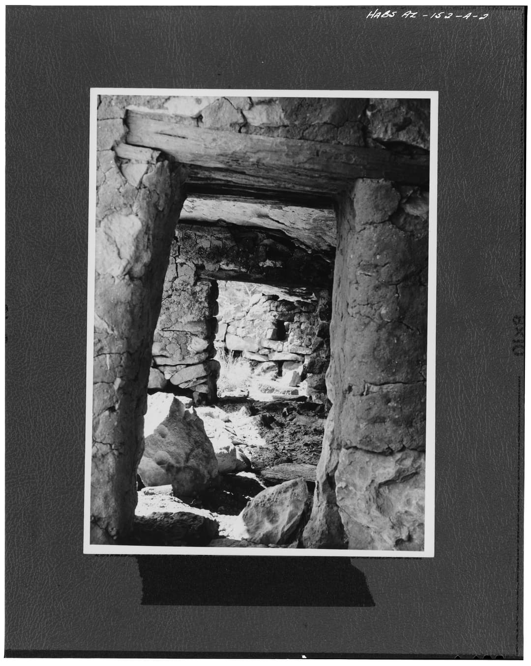 Interior view looking through stone masonry doorways with wooden lintels.