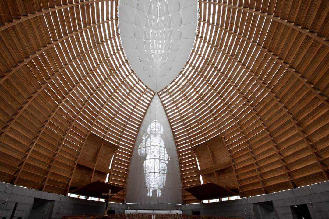 Interior view of the sanctuary showing curved timber ribs and Christ screen.