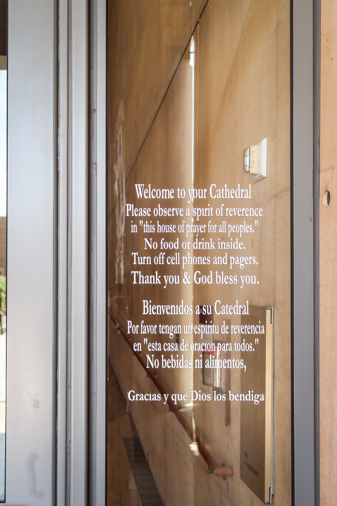 Bilingual welcome sign on a glass entrance door of the cathedral.