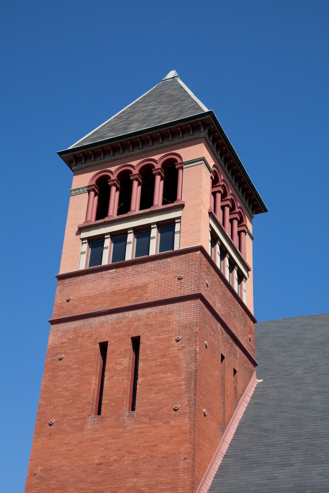 Detail of the Romanesque brick bell tower against a clear blue sky