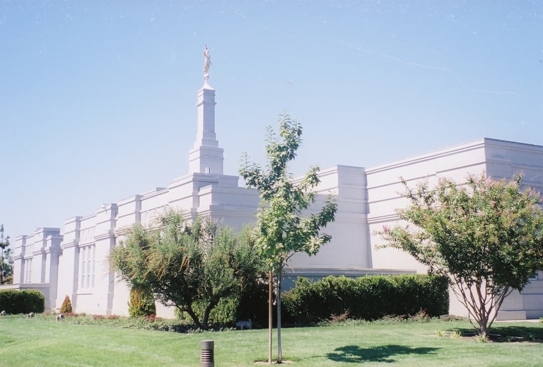 Fresno California Temple, side view with Moroni statue and lush grounds.