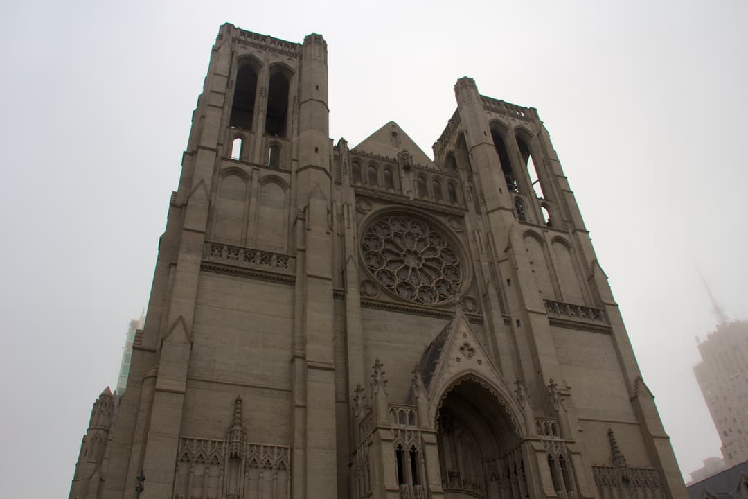 Low-angle view of the main facade and twin towers shrouded in fog.