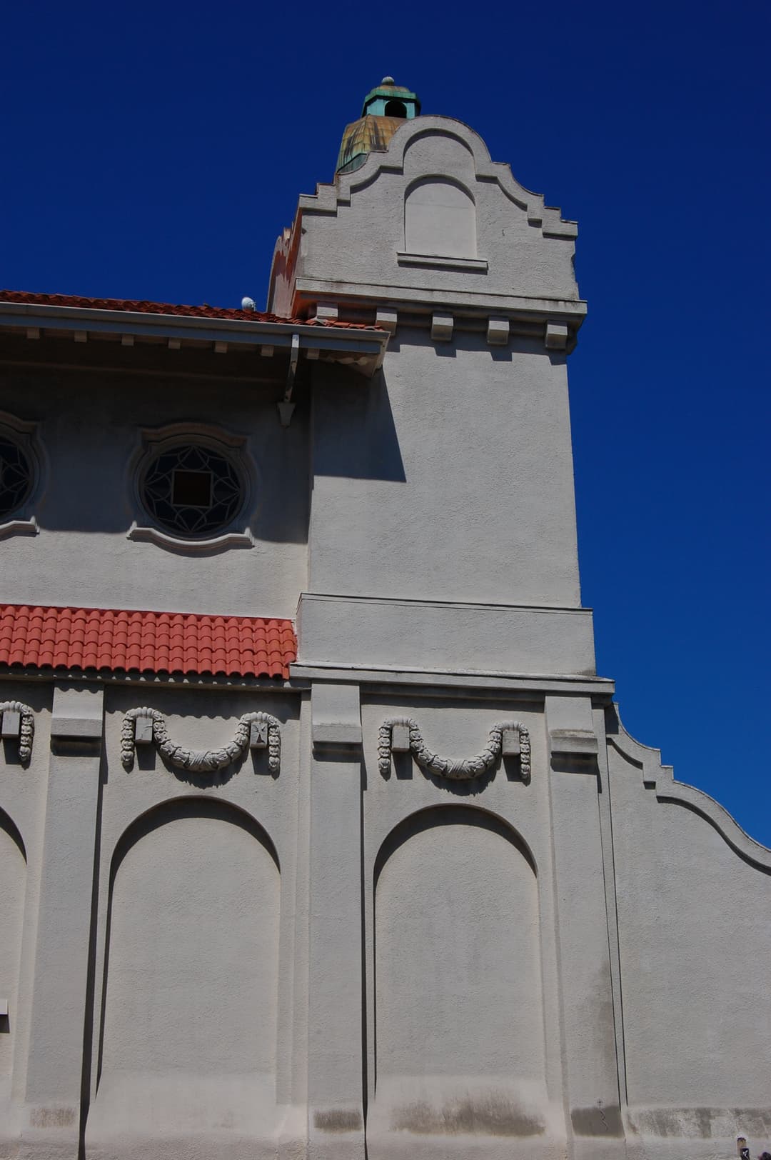 Corner tower with cupola and Mission Revival parapet in bright daylight