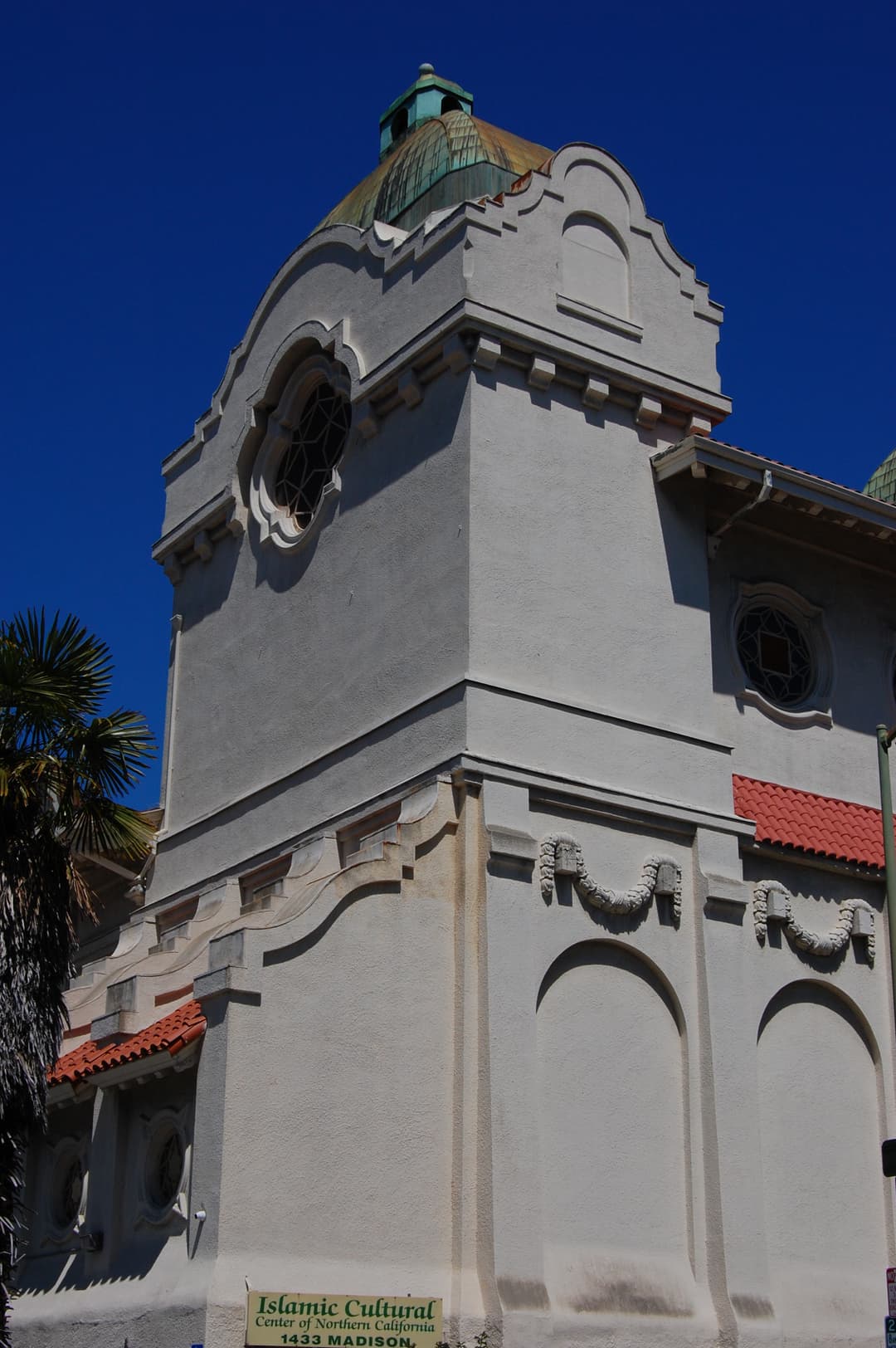 Low-angle view of the Mission Revival tower and copper dome.