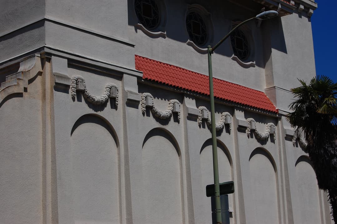 Exterior facade detail with carved festoons, blind arches, and red tile roof
