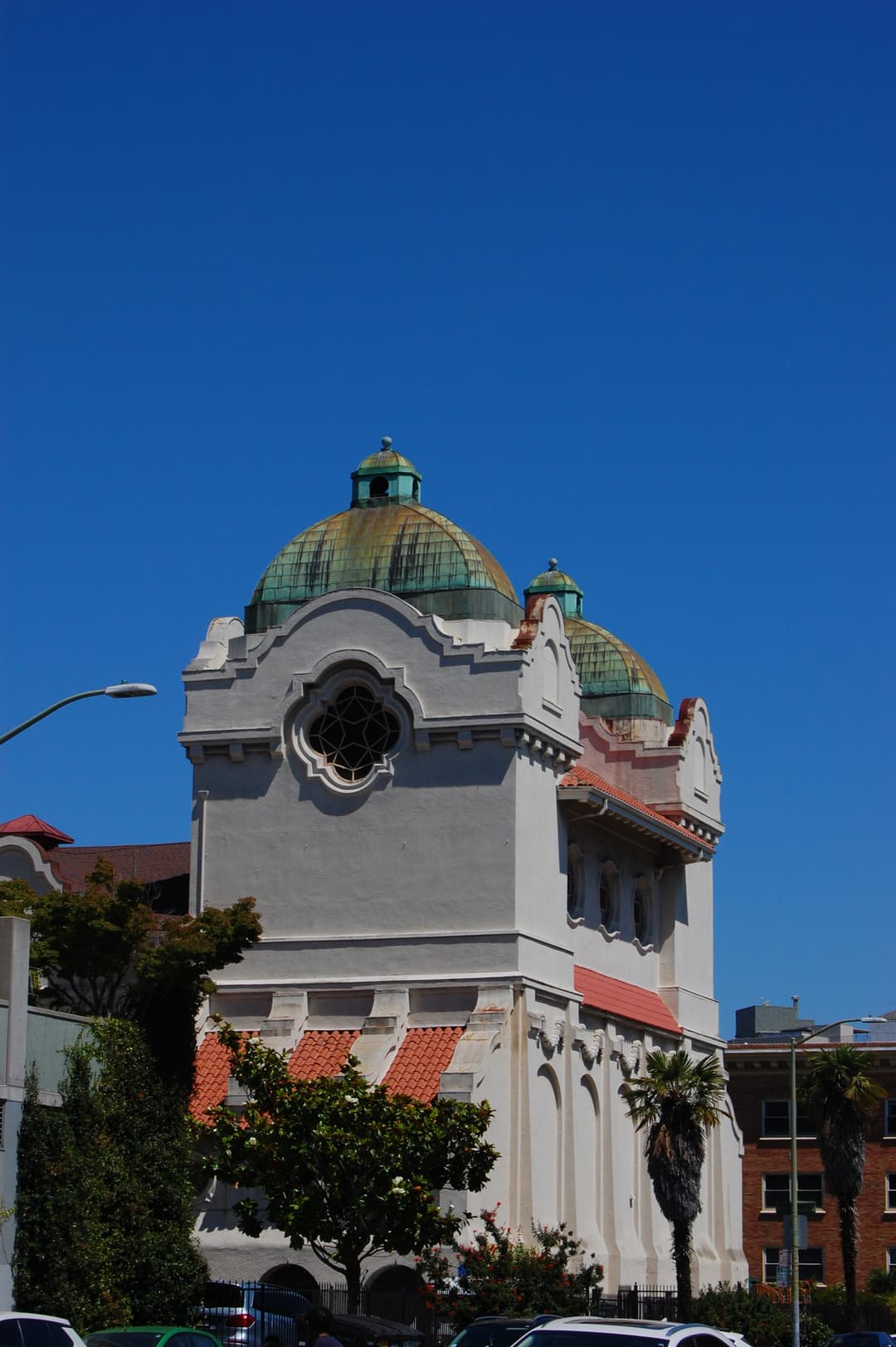 Twin copper domes and Mission Revival parapet under a blue sky