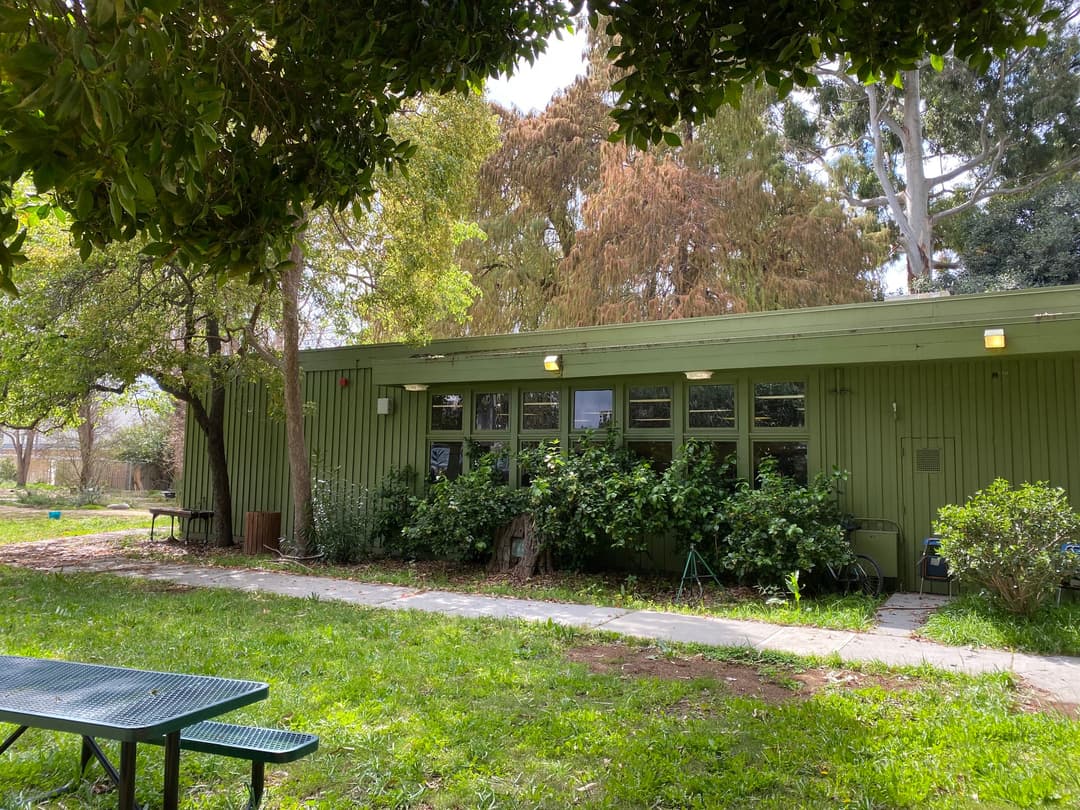 Wide-angle exterior view of the green building and grounds in daylight.