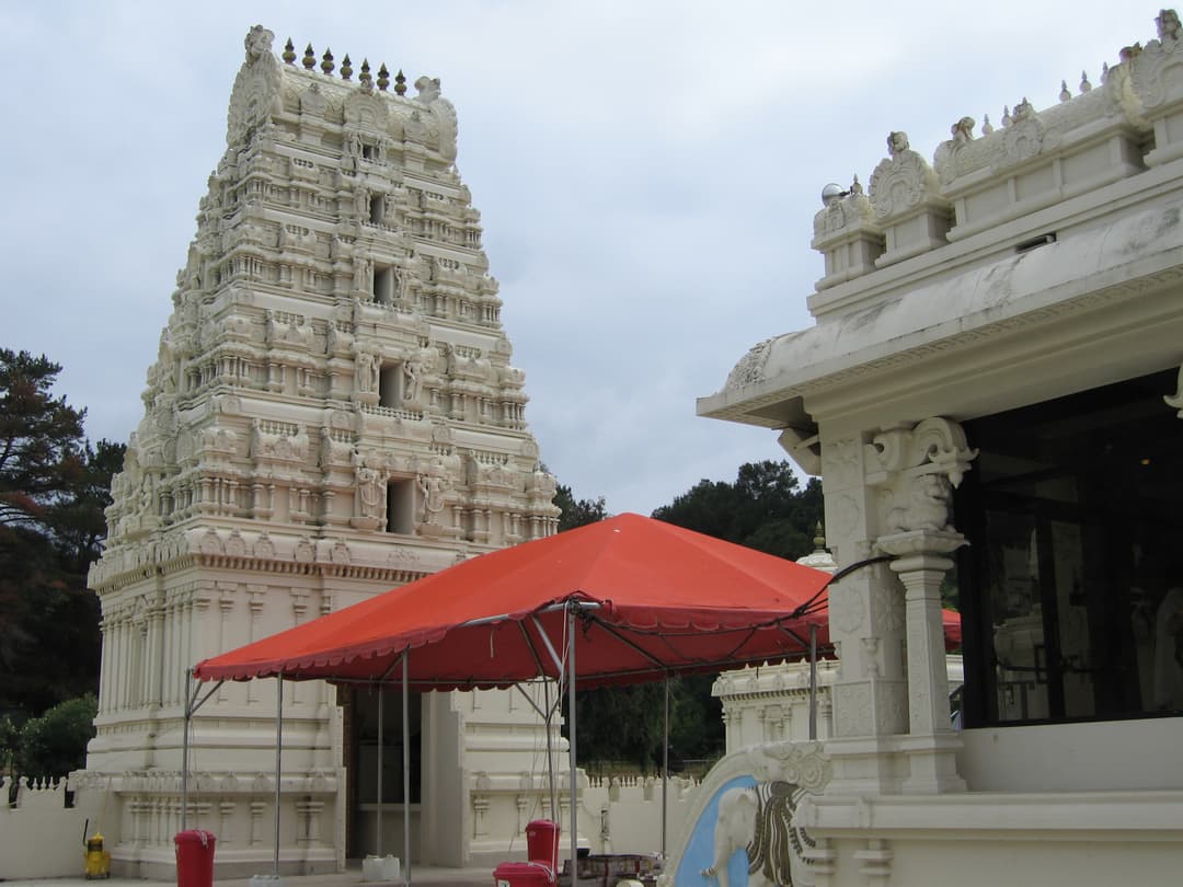Carved white gopuram and temple courtyard with a red canopy