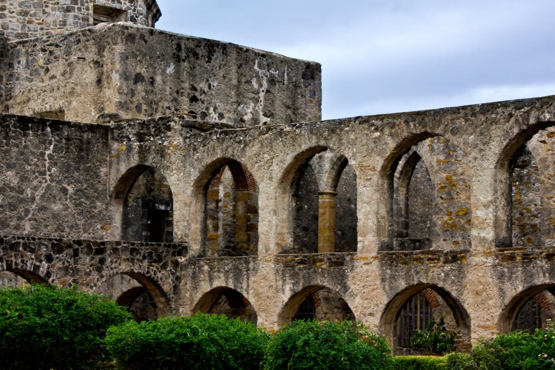 Exterior view of historic two-tiered stone arches and convento grounds.