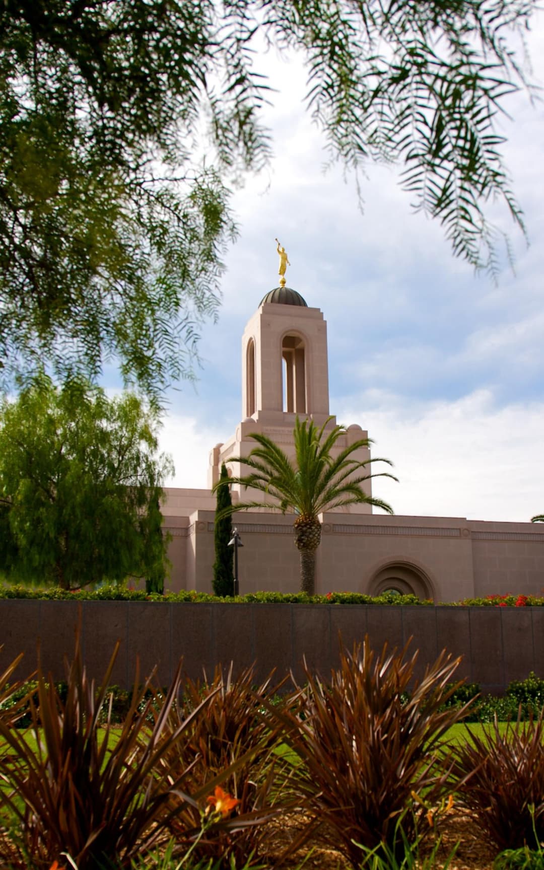 Newport Beach Temple tower with Angel Moroni, grounds, and lush foliage.