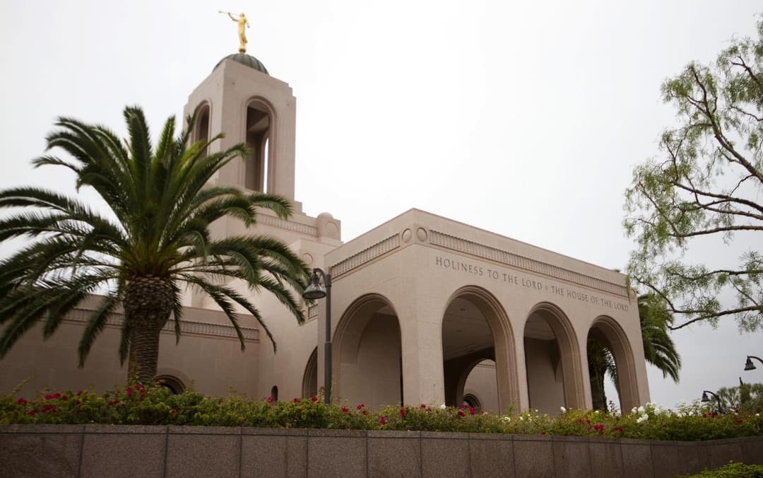Newport Beach Temple exterior with Angel Moroni, arches, and palm trees.