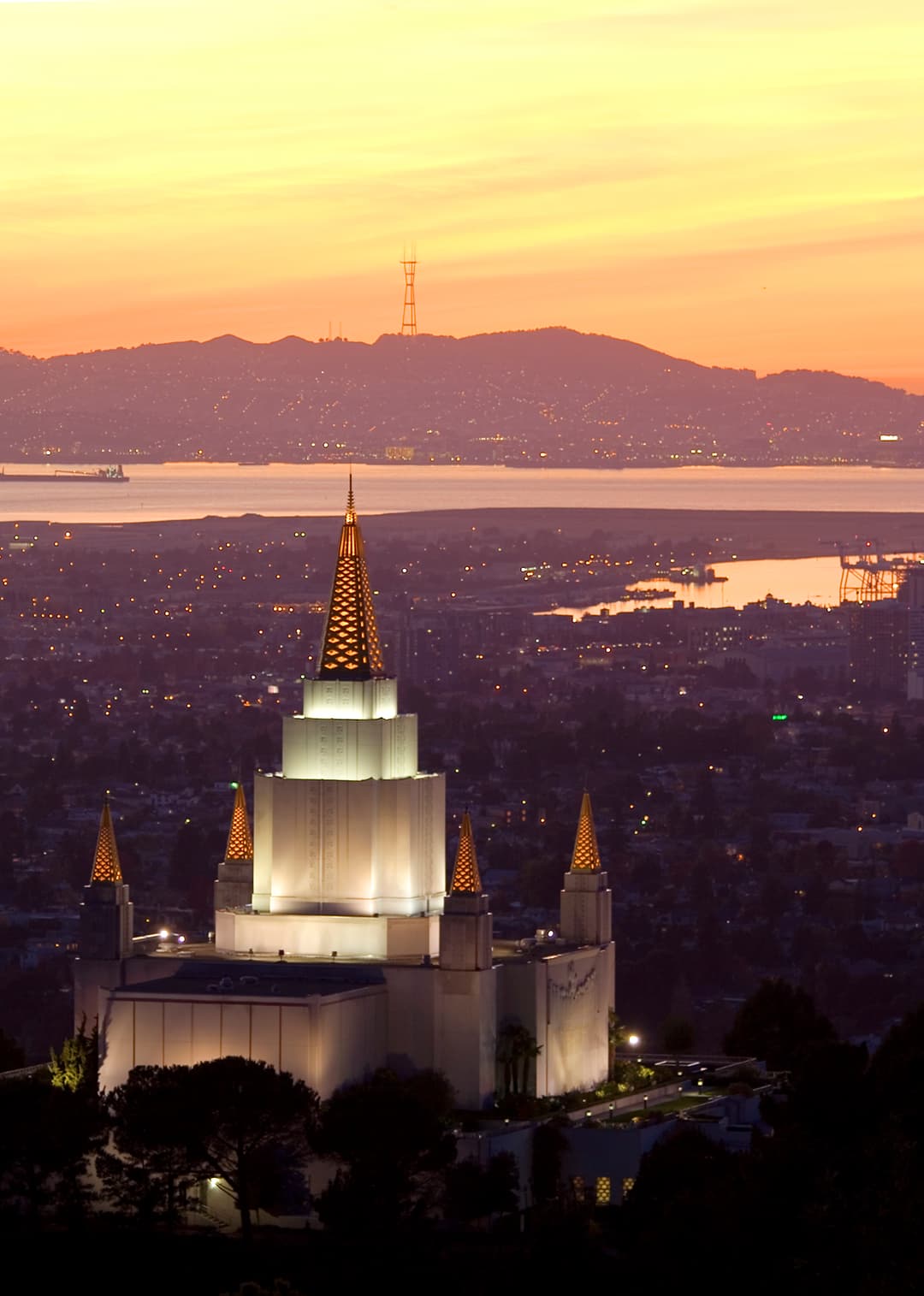 The Oakland California Temple illuminated at twilight, visible across the Bay Area.