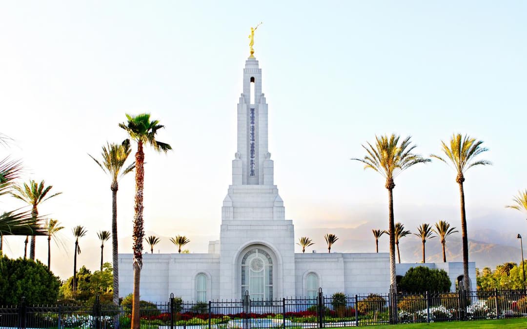 Exterior front view of the Redlands California Temple framed by palm trees.