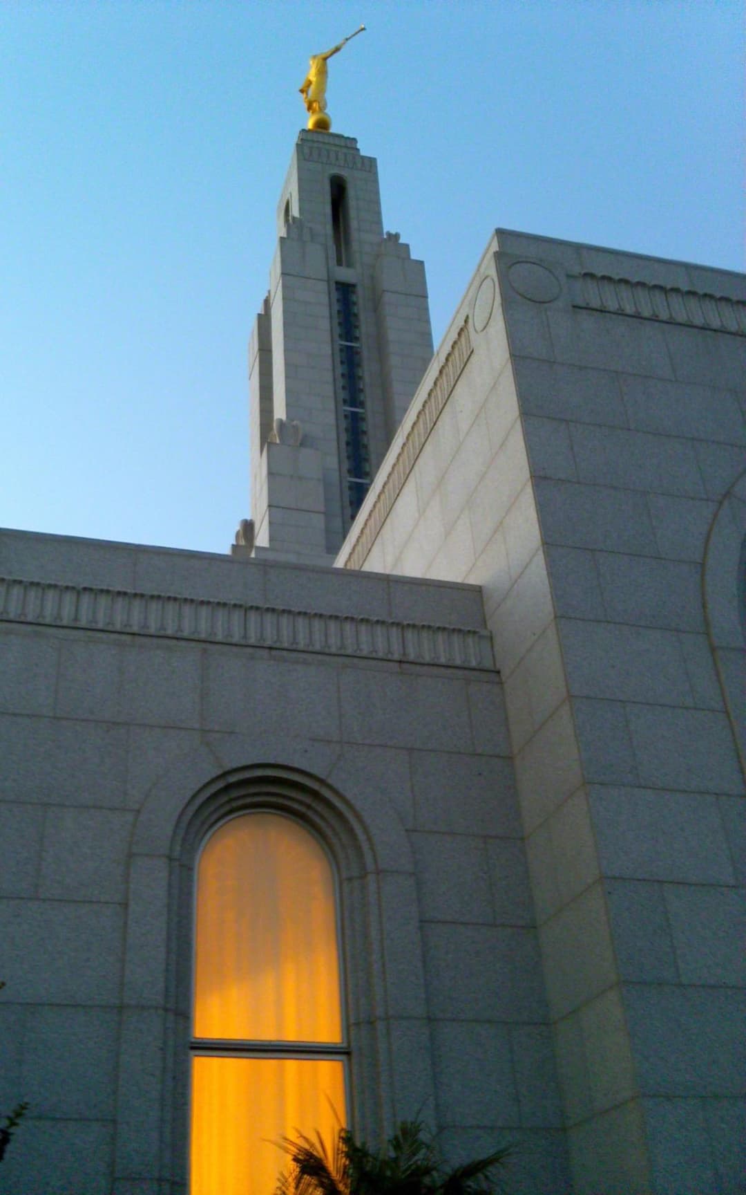 Low-angle view of the spire with Angel Moroni and an illuminated window.