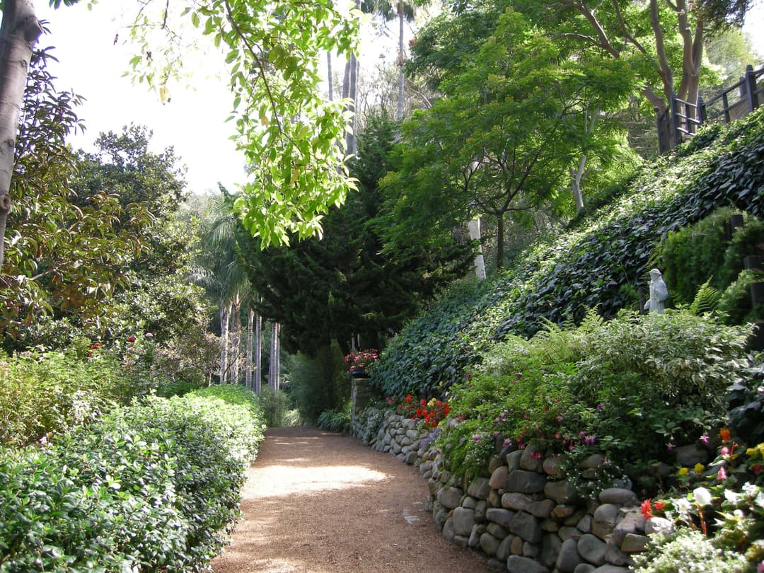 Terraced stone-walled pathway through lush meditation gardens.