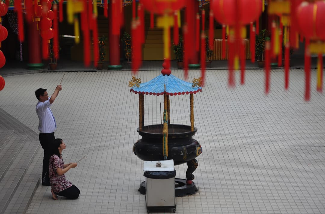 Devotees offering incense at a large burner in the temple courtyard.