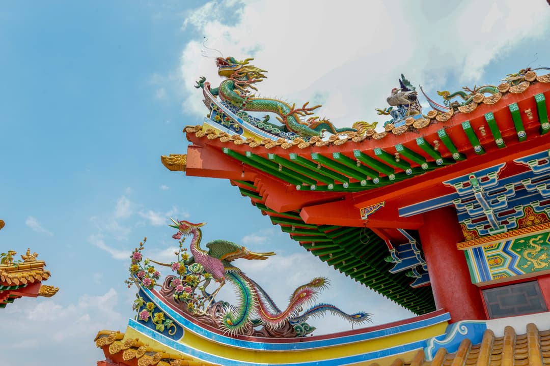 Low-angle view of ornate temple roof with dragon and phoenix sculptures.
