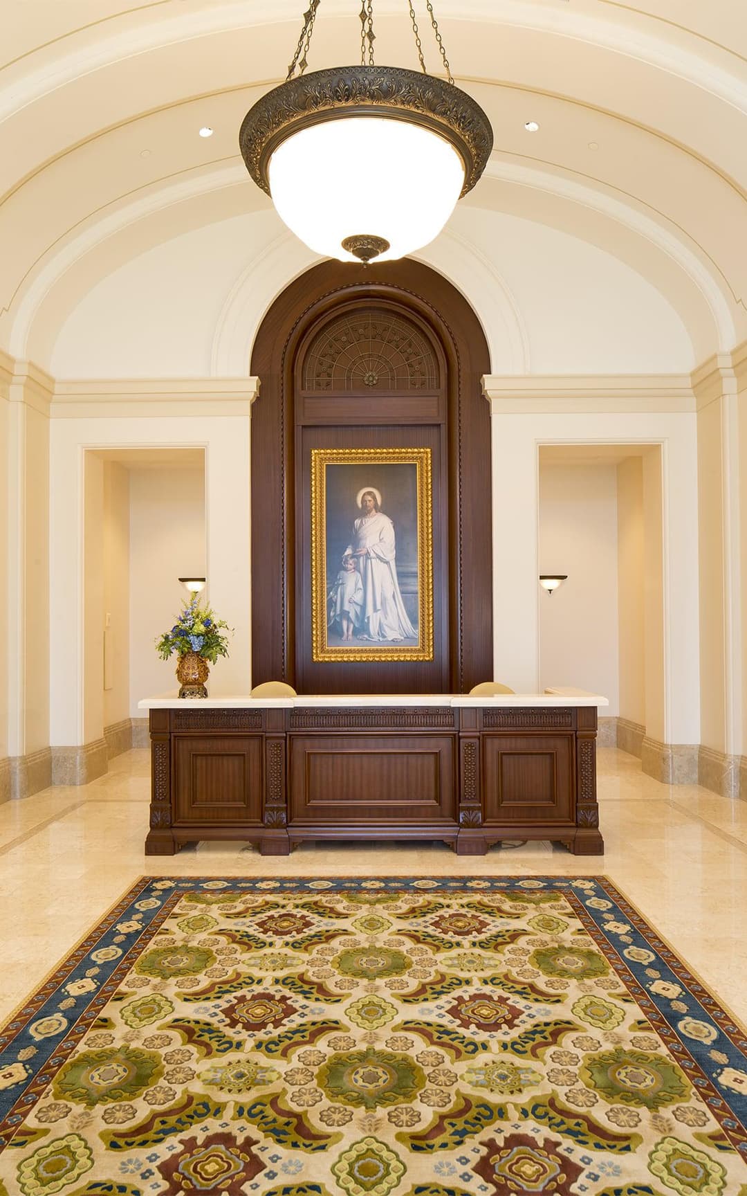 Fort Collins Temple interior: reception desk, Christ painting, and chandelier.
