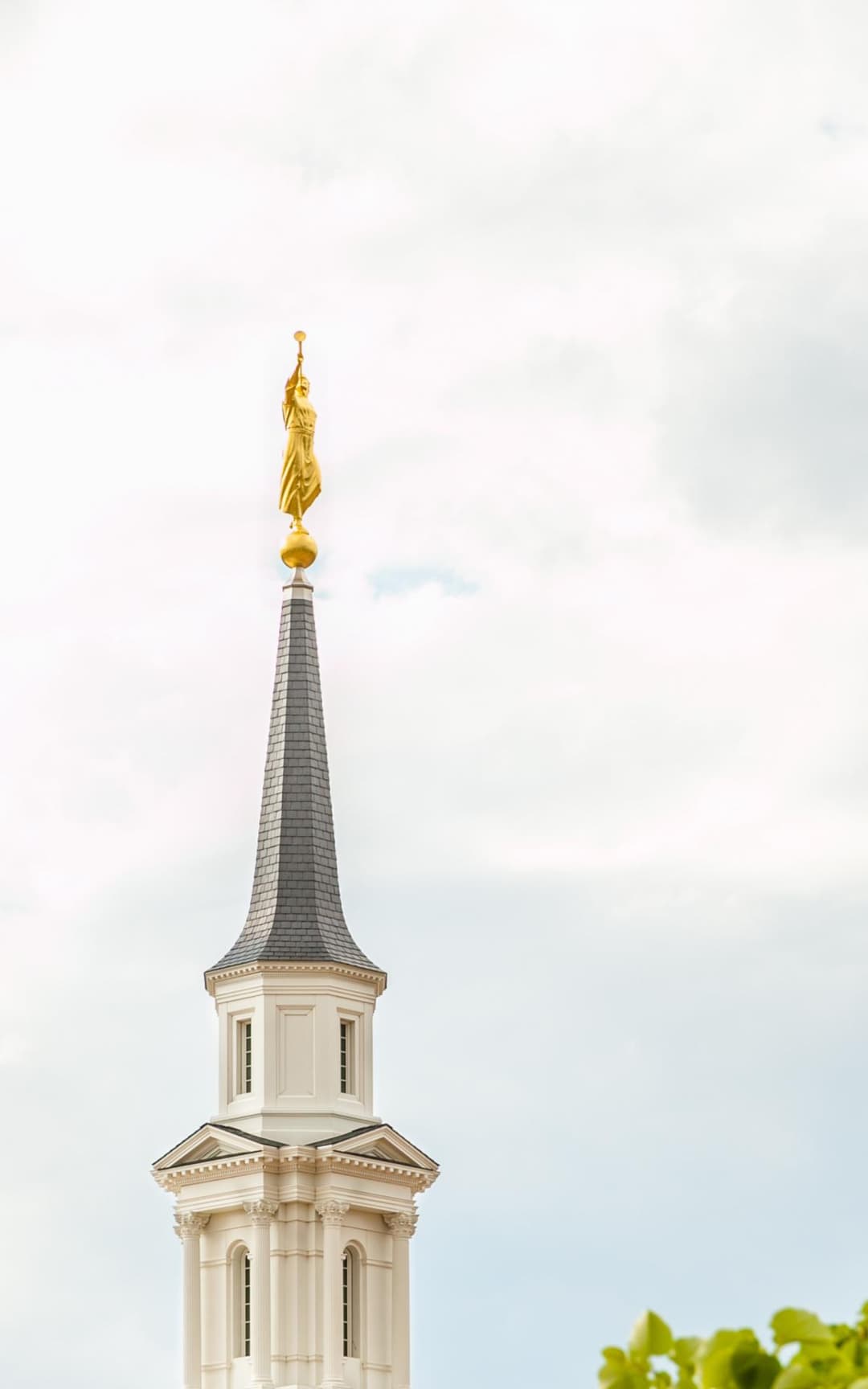 Hartford CT Temple spire and Angel Moroni statue against a cloudy sky.