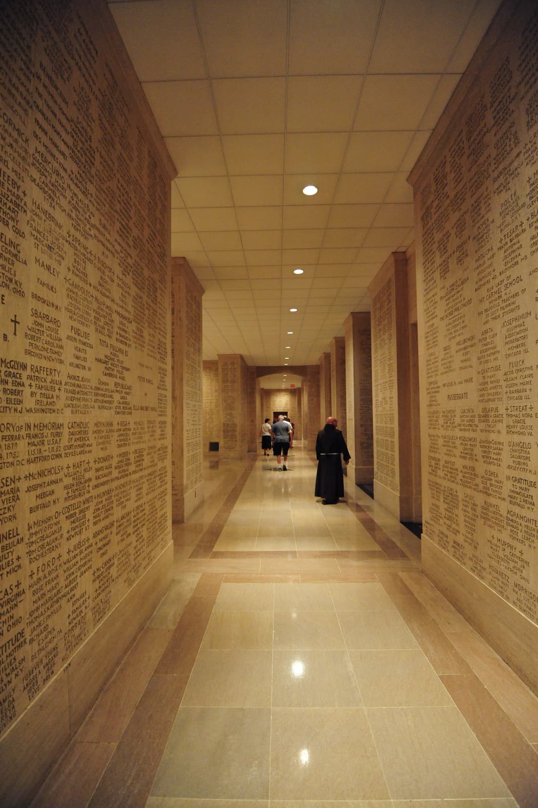 Corridor lined with engraved memorial walls in the Crypt of the Basilica.