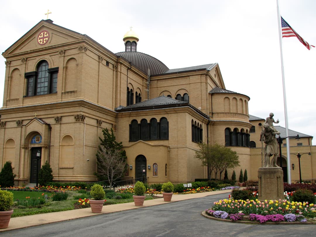 Exterior view of the Franciscan Monastery, featuring its dome and gardens.