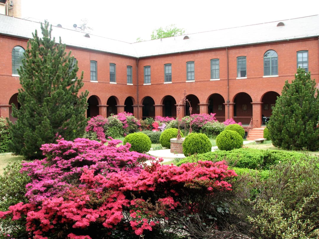 Cloister garden with blooming azaleas surrounded by red brick arcades.