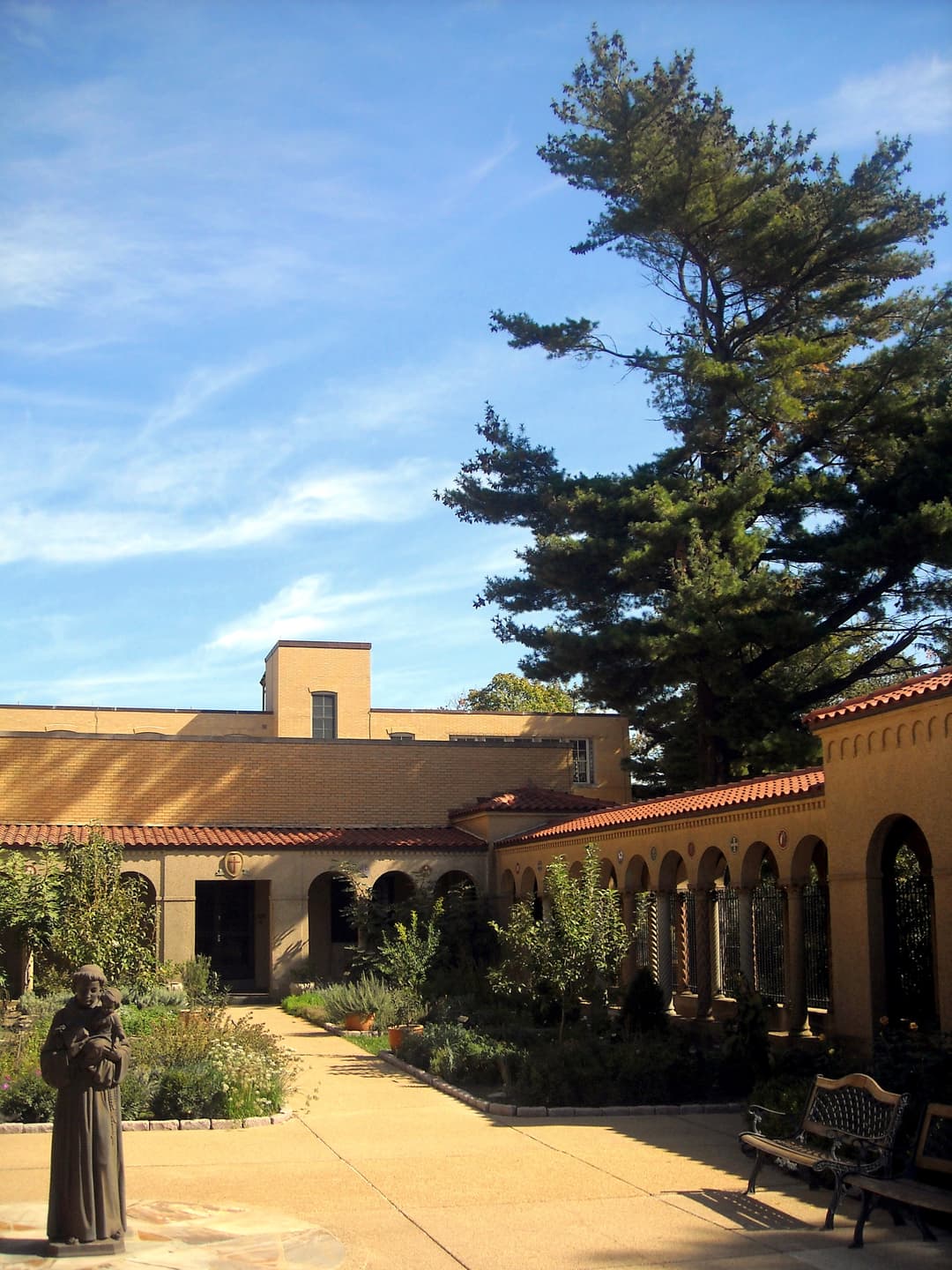 Courtyard garden with arcaded cloister walkway in bright daylight.
