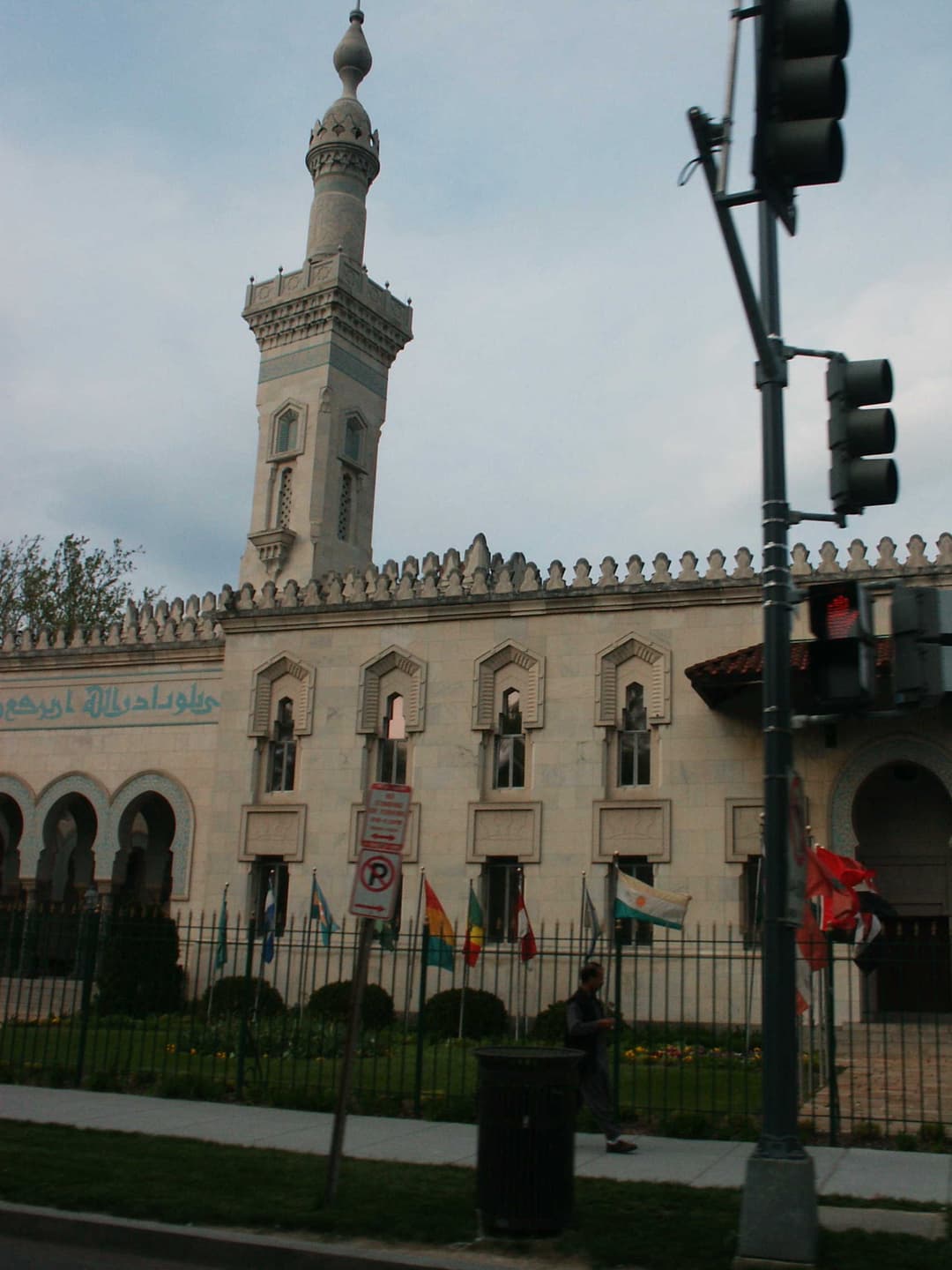 Street view of the Islamic Center minaret, facade, and flag-lined fence.