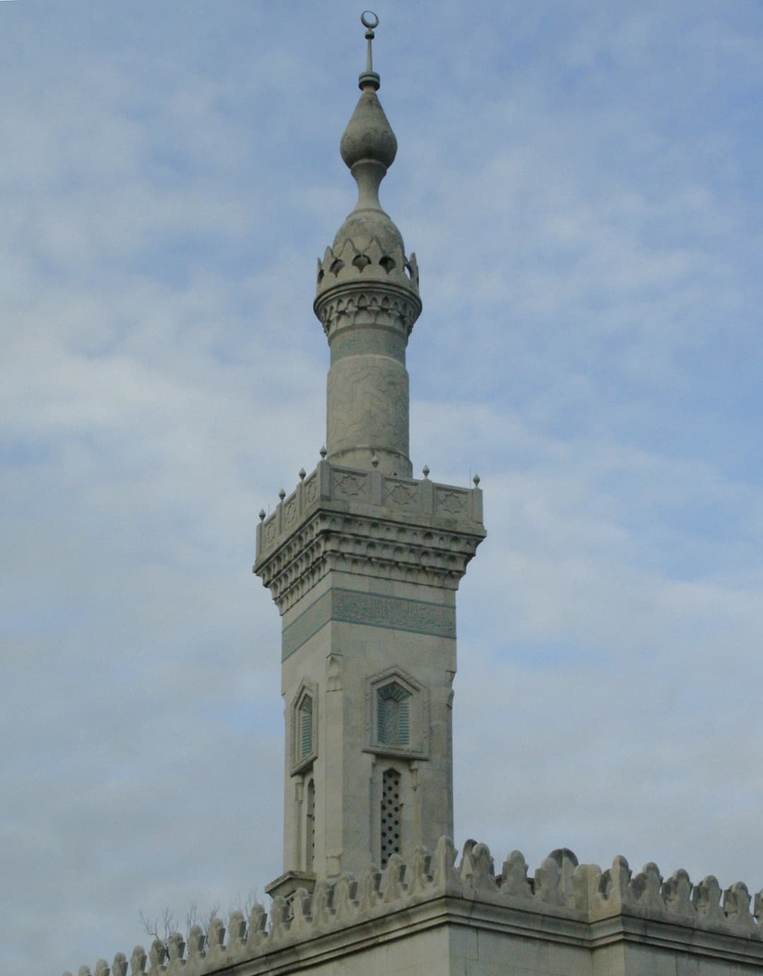 Low-angle view of the Neo-Mamluk minaret against a cloudy blue sky.