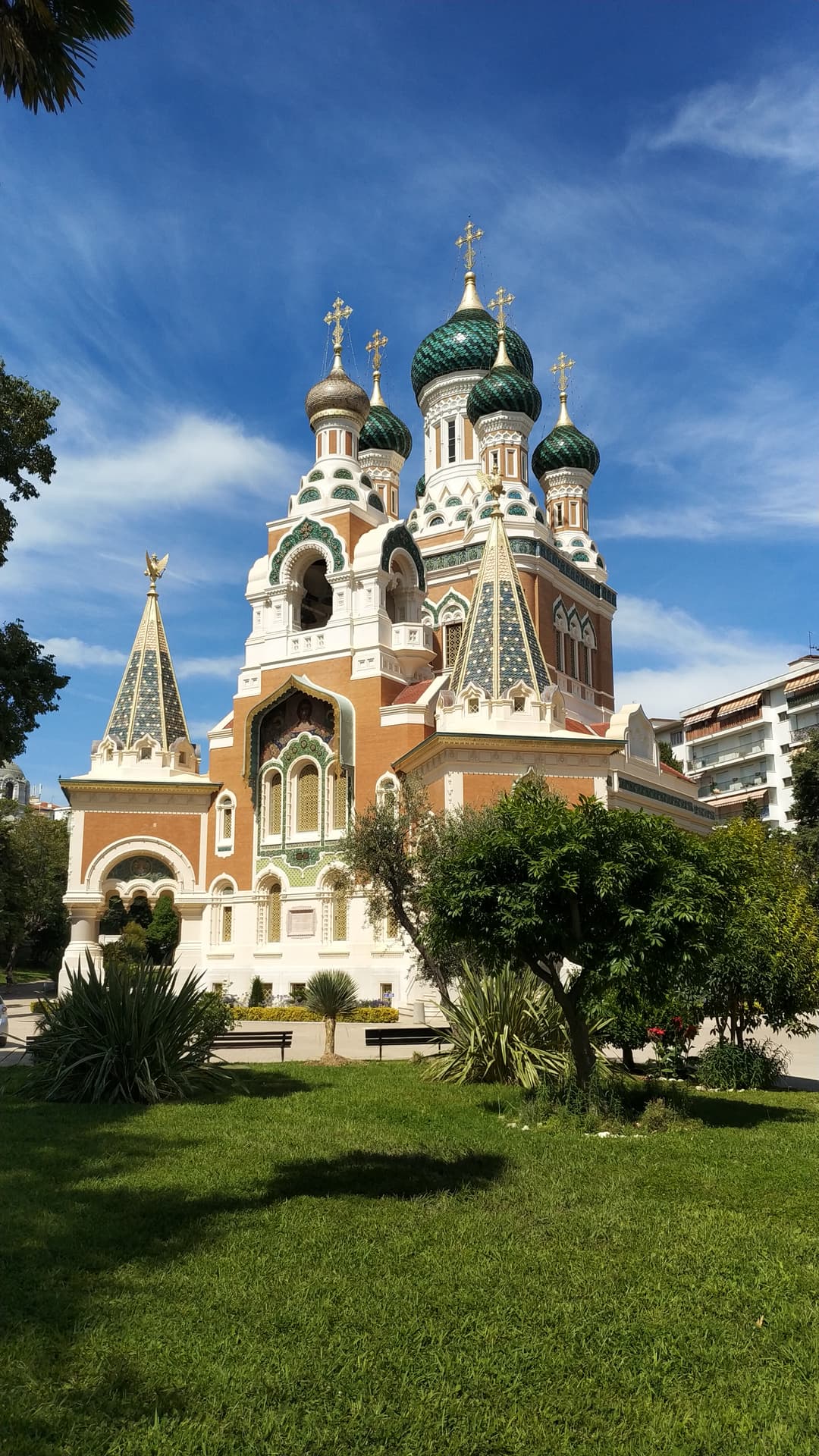 Exterior view of the cathedral with ornate domes, spires, and garden lawn.