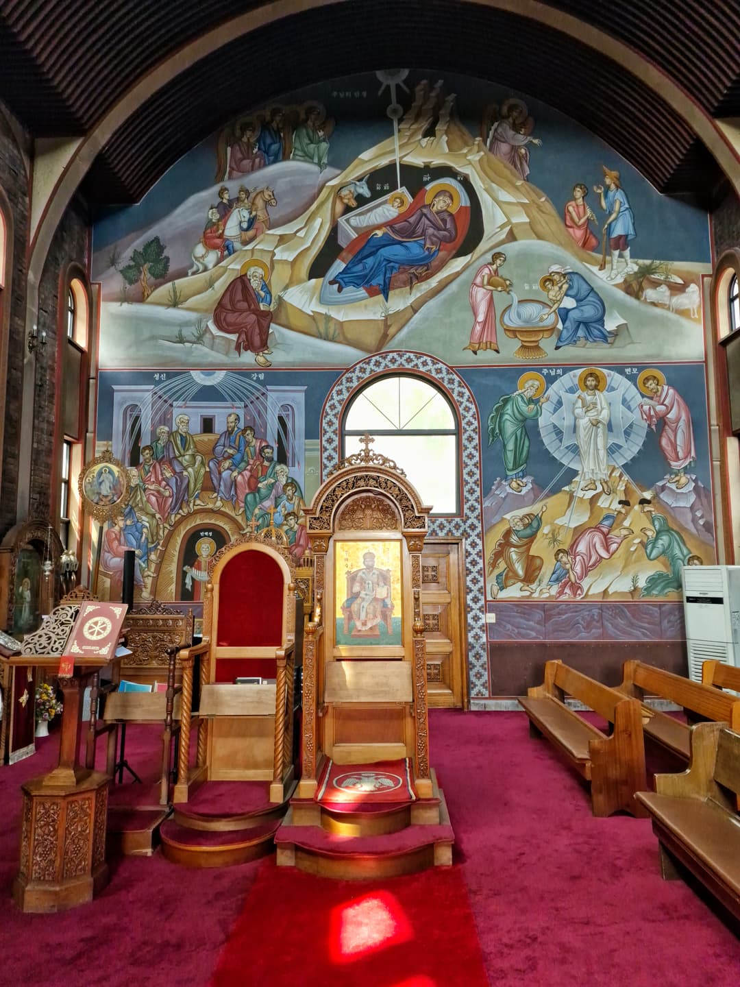 Interior view featuring the bishop's throne and biblical wall frescoes