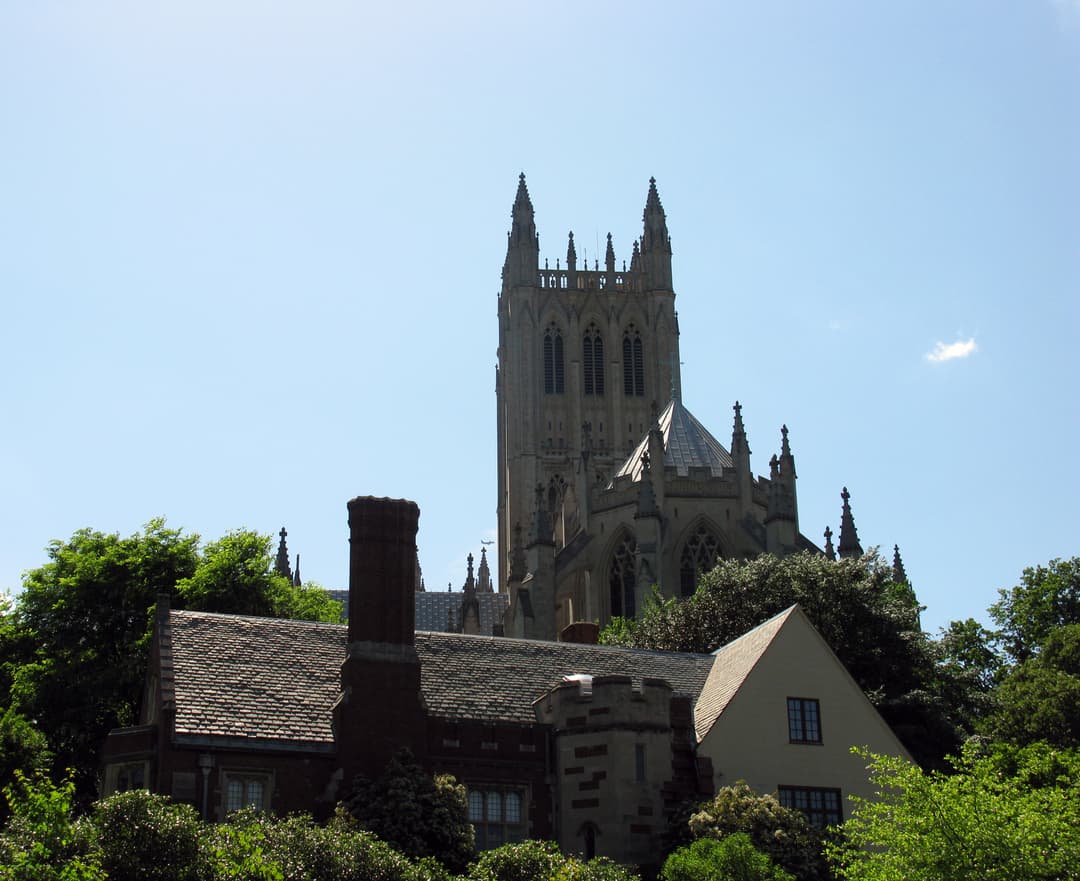 Exterior view of Gloria in Excelsis Tower rising above roofs and trees.