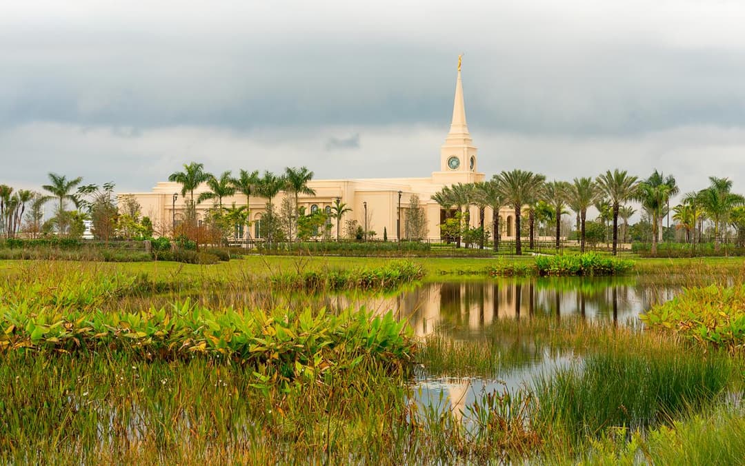 Fort Lauderdale Florida Temple and spire reflected in a pond under an overcast sky.