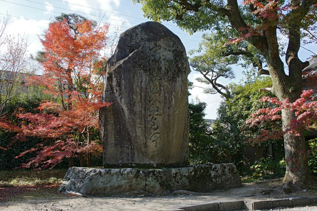 Carved stone monument framed by autumn maple trees on the temple grounds.