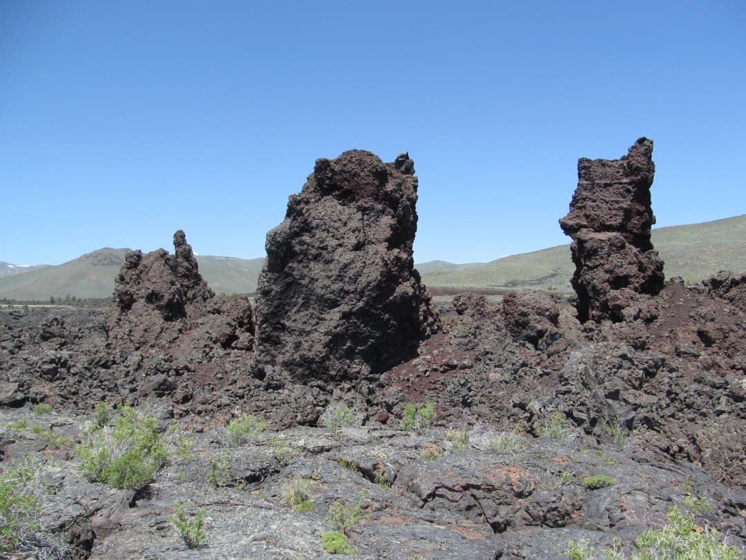 Basalt spatter chimneys rising from the rugged lava field in midday sun.