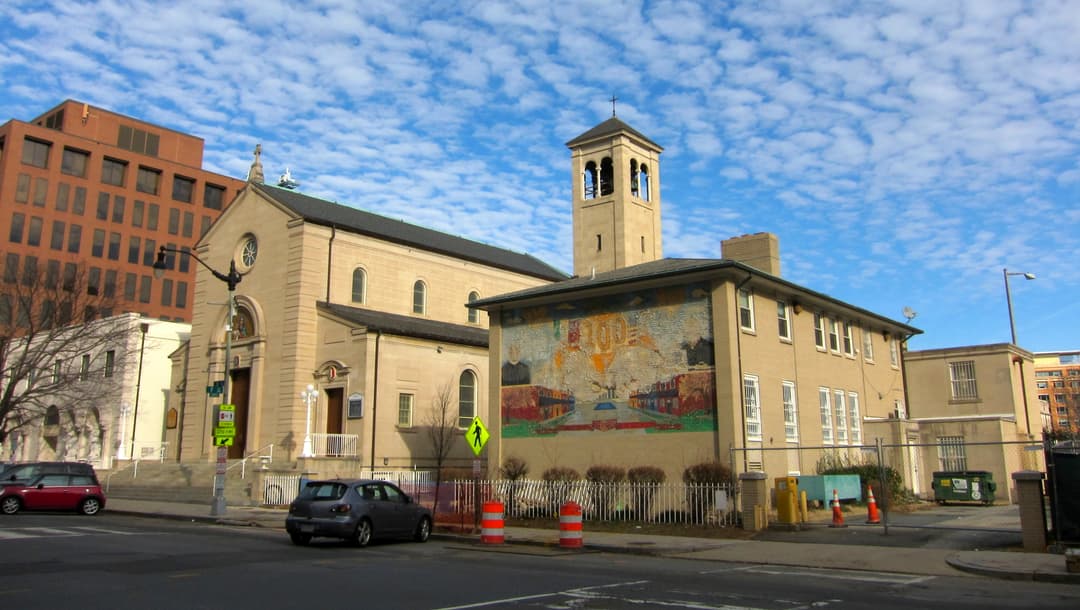 Exterior view of the church, bell tower, and adjacent building with mural