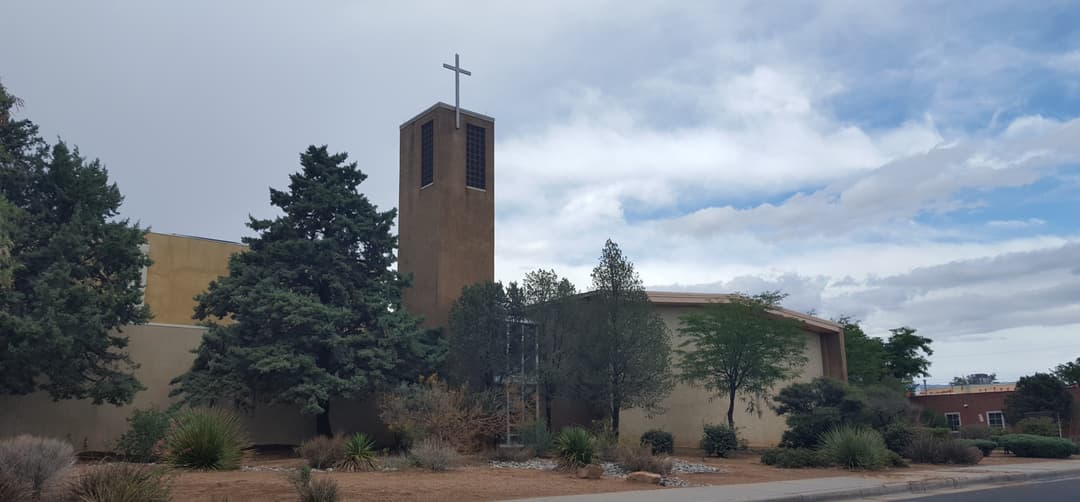 Exterior view of the church and bell tower with cross under an overcast sky