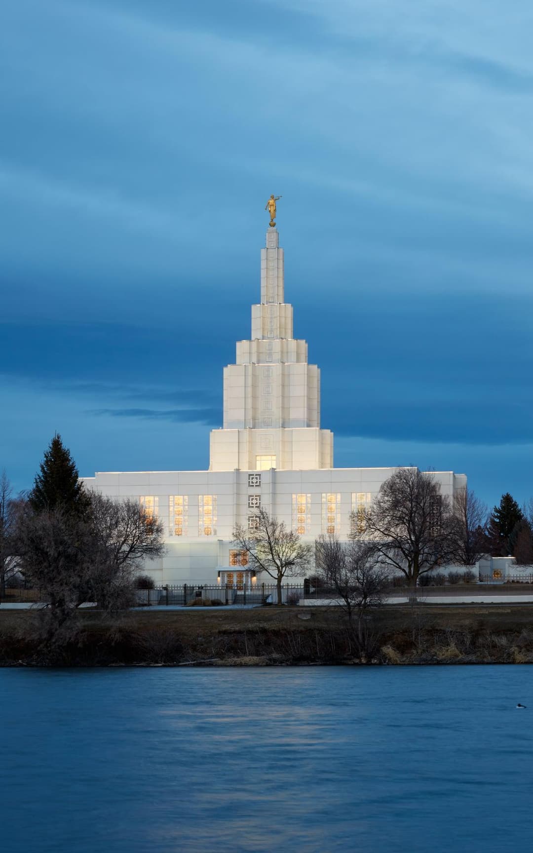 A twilight view of the illuminated temple across the calm river.